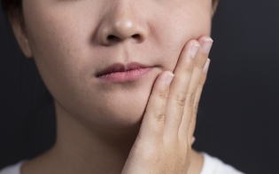Child with toothache holding cheek