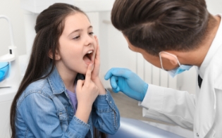 Child pointing to chipped or broken permanent tooth