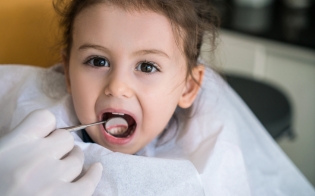 Pediatric dentist examing child with a lost filling