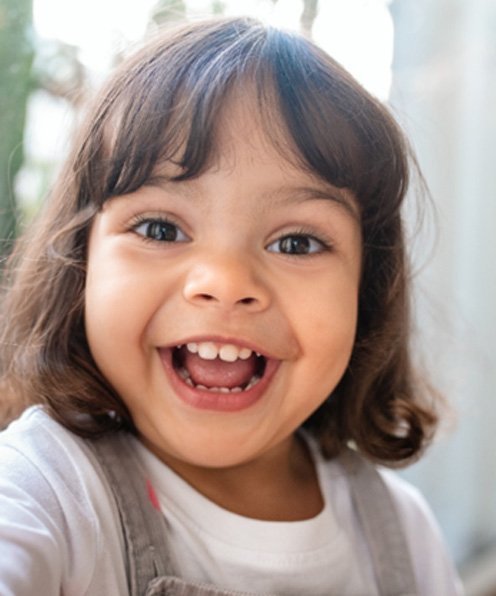 Little girl smiling in front of a window