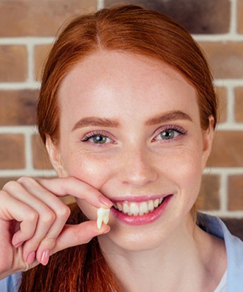 young woman holding extracted wisdom tooth