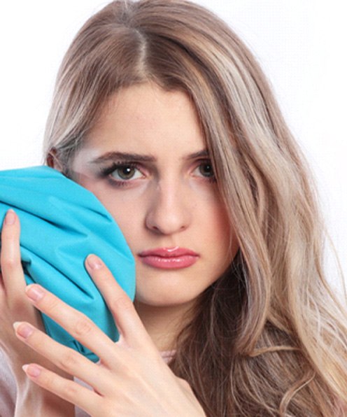 young woman holding ice pack to face