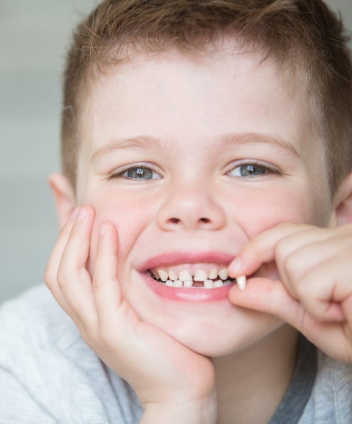 Child smiling and holding tooth after extraction