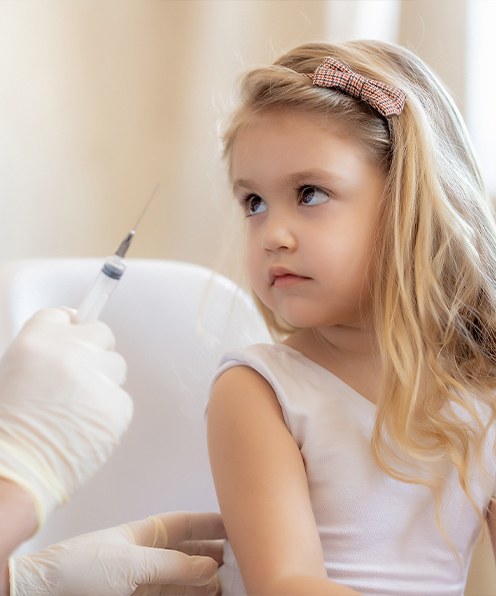Child fearful of doctor holding a needle
