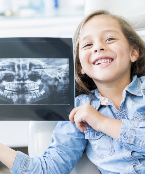 Child smiling and holding x-ray after pulp therapy