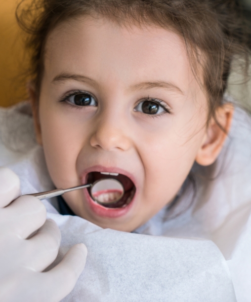 Dentist examining child's smile after tooth colored filling treatment