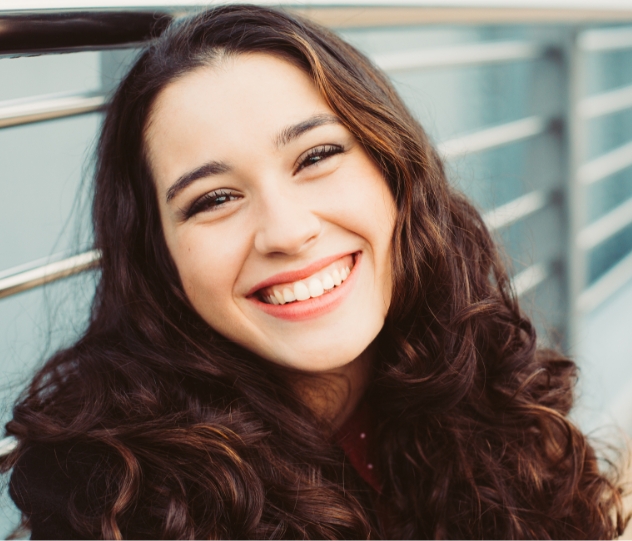 Young woman smiling after emergency kids' dentistry