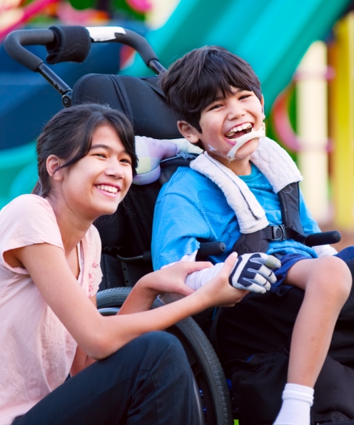 Child in wheelchair laughing with friend after special needs dentistry visit