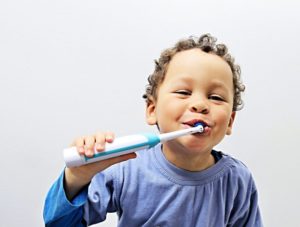 smiling child holding an electric toothbrush
