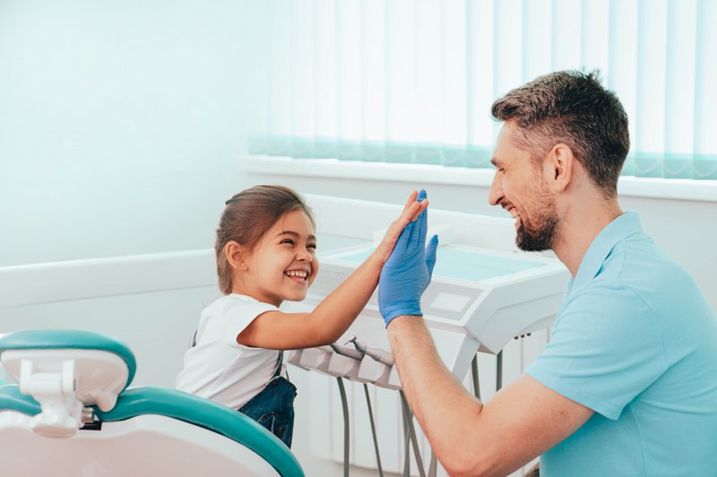 Young girl high-fiving dentist in dental exam room