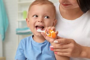 Mom helping her child brush his teeth with modified toothbrush