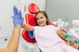 Young girl high fiving her dentist after getting dental sealants